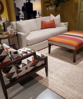 stylish living room setup with a white couch, colorful geometric patterned chairs and ottoman, and accents like lamps and artwork